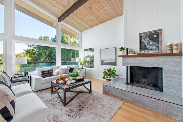 living room featuring beamed ceiling, a large fireplace, wood ceiling, and light hardwood / wood-style floors