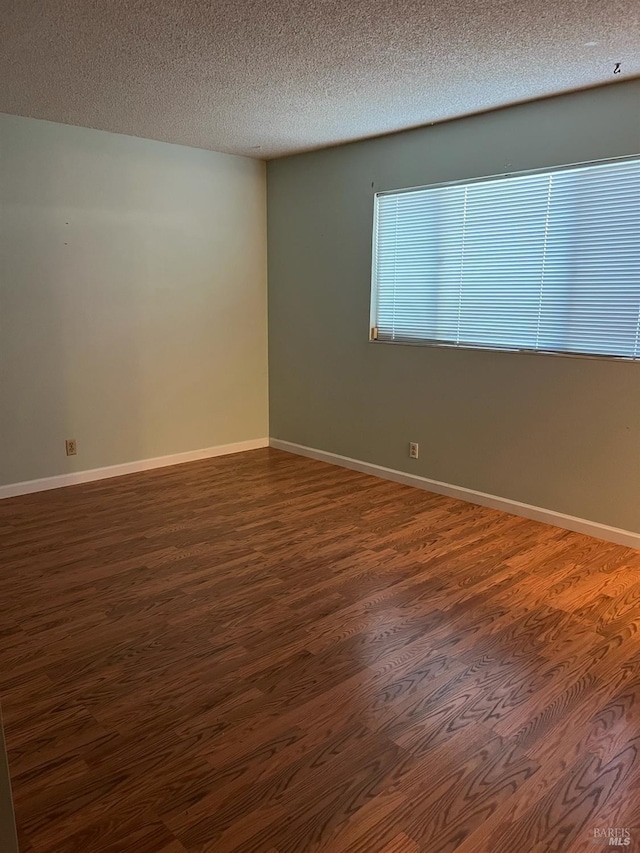 empty room featuring a textured ceiling and dark hardwood / wood-style flooring