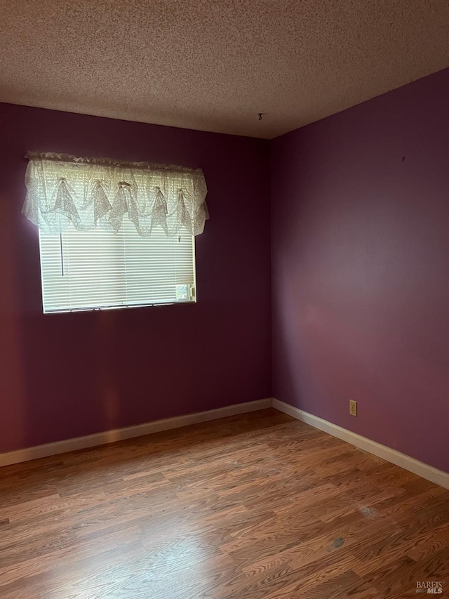 unfurnished room with wood-type flooring and a textured ceiling