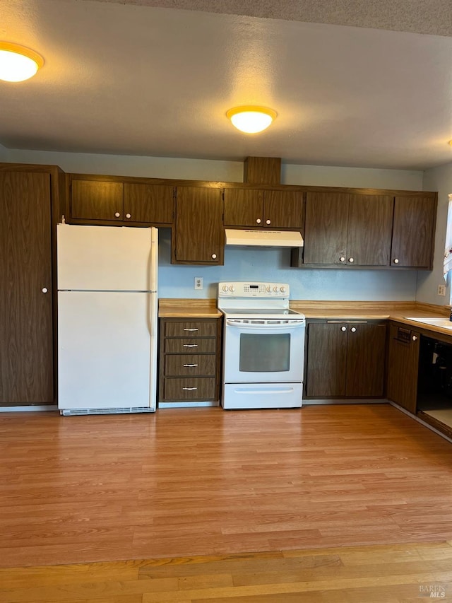 kitchen with light wood-type flooring, a textured ceiling, and white appliances