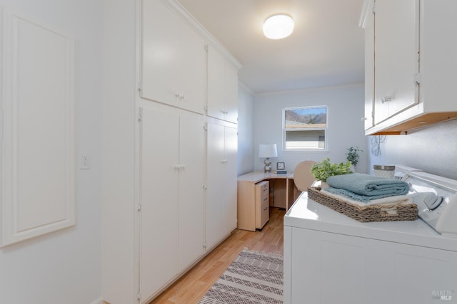 clothes washing area featuring crown molding, washing machine and clothes dryer, cabinet space, and light wood-style floors