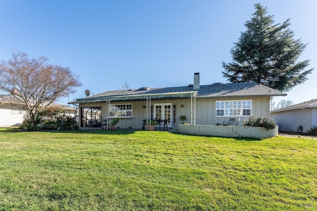 rear view of property featuring board and batten siding, french doors, a yard, and a chimney