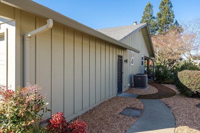 view of home's exterior featuring board and batten siding, a shingled roof, and central AC unit