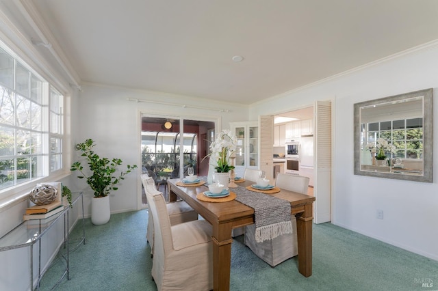 carpeted dining room with plenty of natural light, ornamental molding, and baseboards