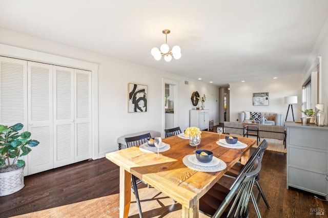 dining space featuring dark wood-type flooring, crown molding, and an inviting chandelier