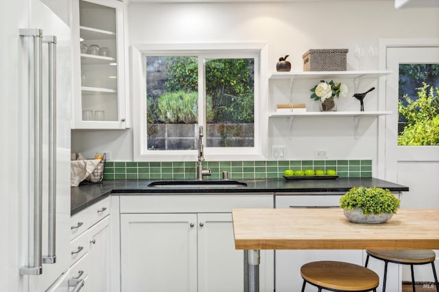 kitchen featuring a kitchen breakfast bar, sink, high quality fridge, and white cabinetry