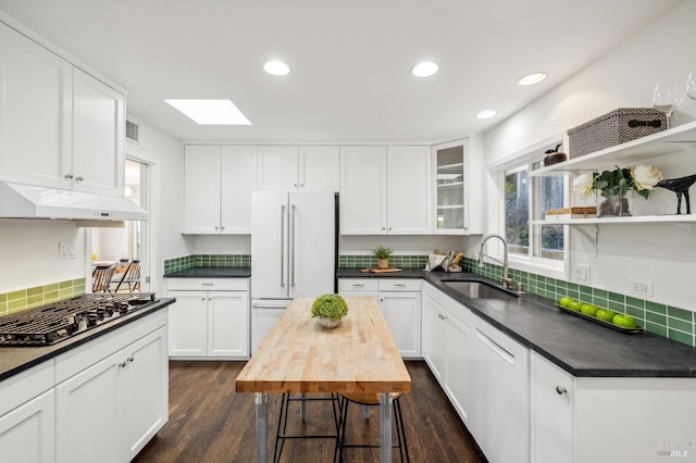 kitchen with white cabinetry, a skylight, white appliances, dark wood-type flooring, and sink