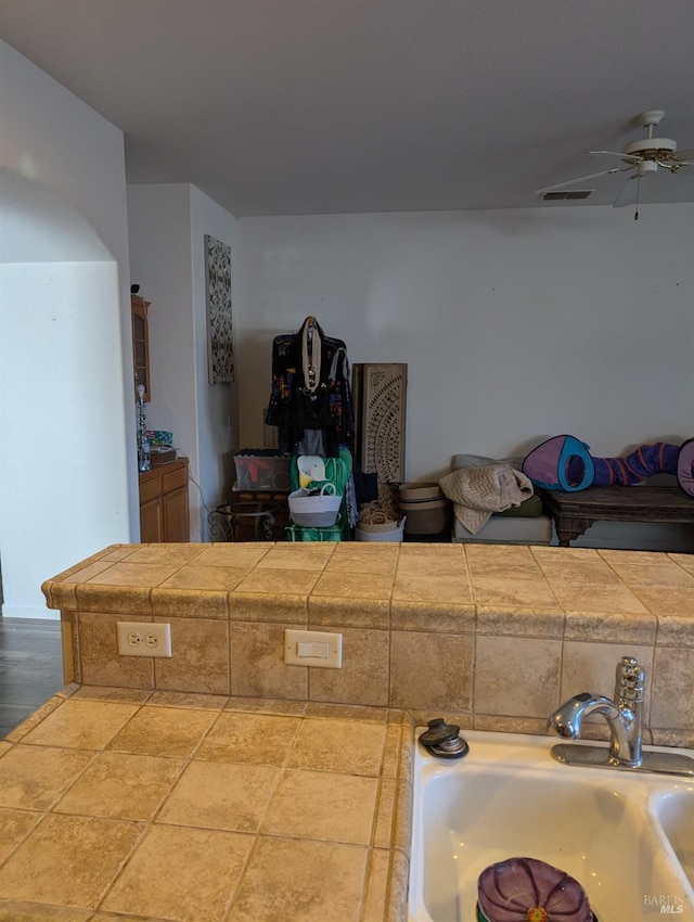 interior space featuring tile counters, ceiling fan, and sink