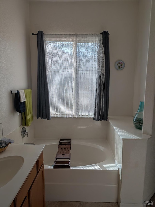 bathroom with plenty of natural light, a washtub, and vanity