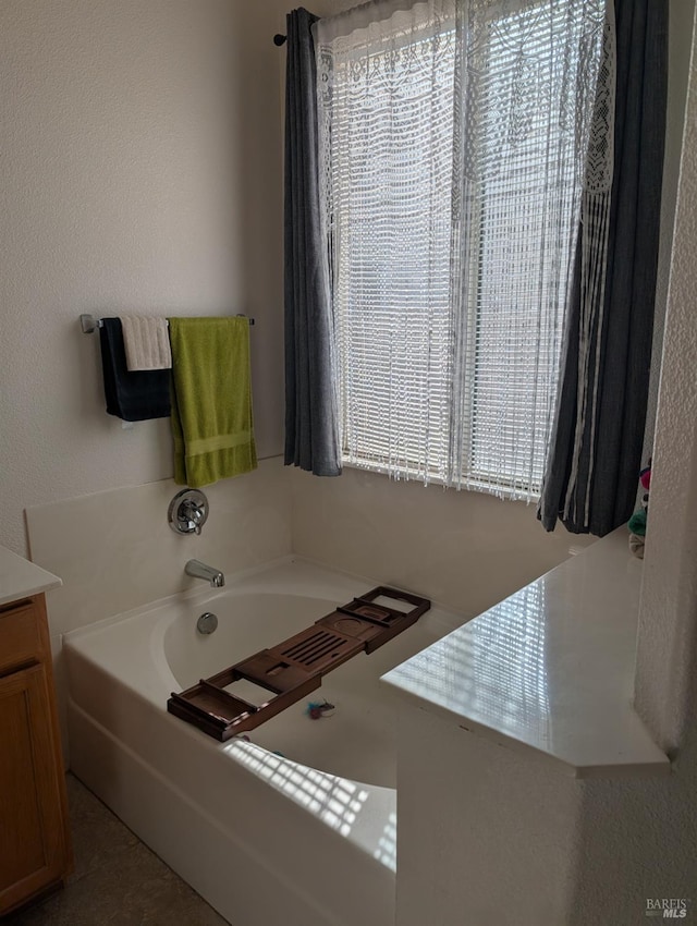 bathroom with tile patterned flooring, vanity, and a tub