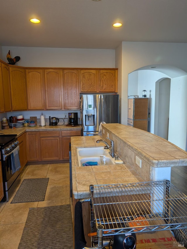 kitchen featuring light tile patterned floors, stainless steel appliances, tile countertops, and sink