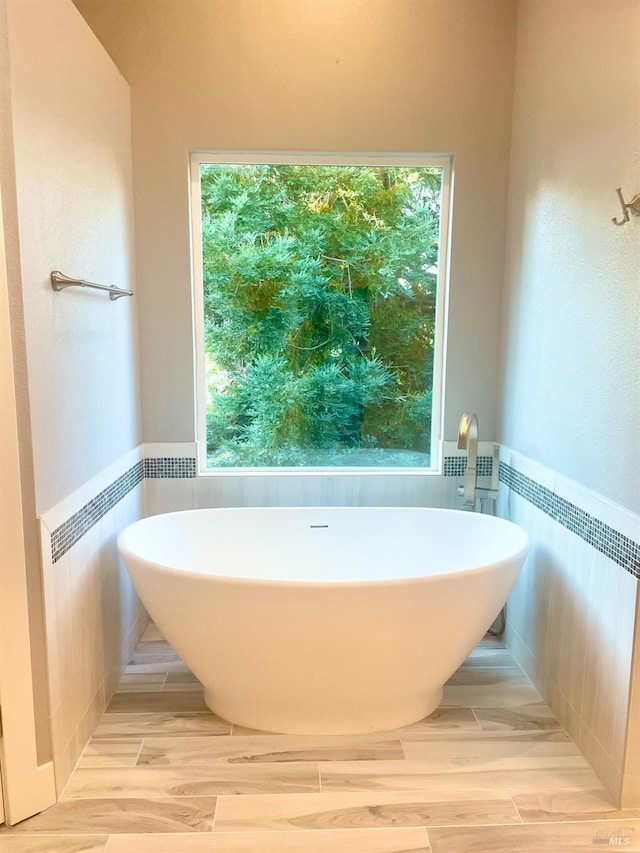 bathroom featuring a washtub, hardwood / wood-style floors, and tile walls