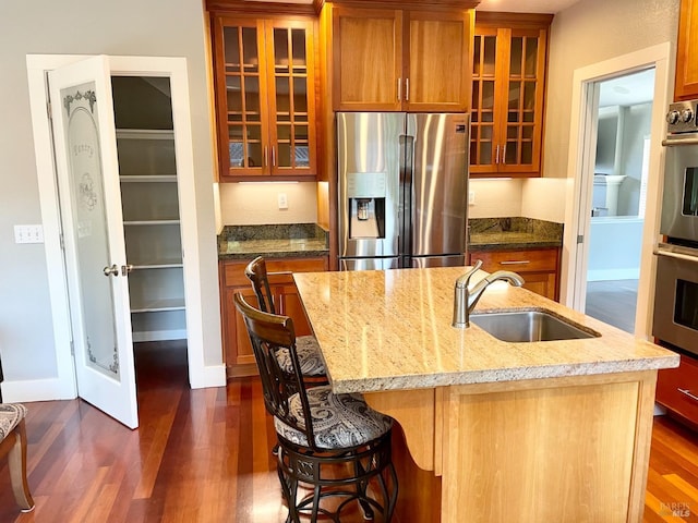 kitchen with an island with sink, sink, a kitchen breakfast bar, dark hardwood / wood-style flooring, and stainless steel appliances