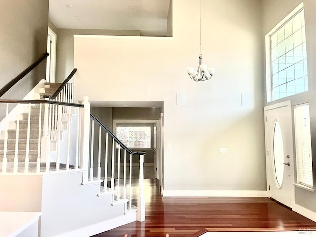 entryway featuring dark hardwood / wood-style floors, a chandelier, and a towering ceiling