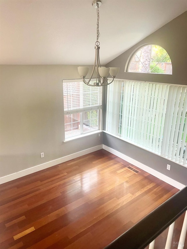 unfurnished dining area featuring an inviting chandelier, hardwood / wood-style floors, and vaulted ceiling