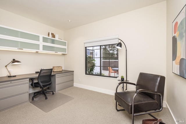 office area with built in study area, light colored carpet, and baseboards