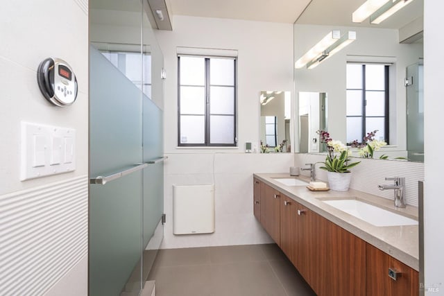 bathroom featuring a wealth of natural light, tile patterned flooring, a sink, and tile walls