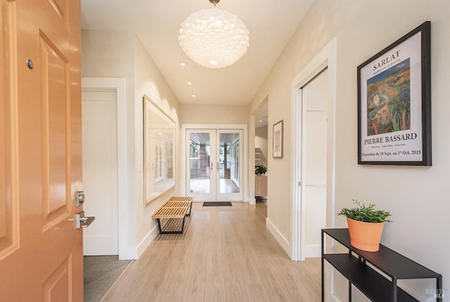 corridor featuring french doors, baseboards, and light wood finished floors