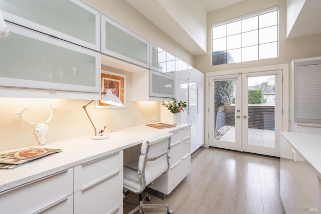 office featuring french doors, built in study area, and light wood finished floors