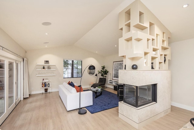 living area featuring baseboards, vaulted ceiling, french doors, light wood-type flooring, and a fireplace