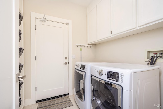 clothes washing area featuring cabinet space and washer and clothes dryer