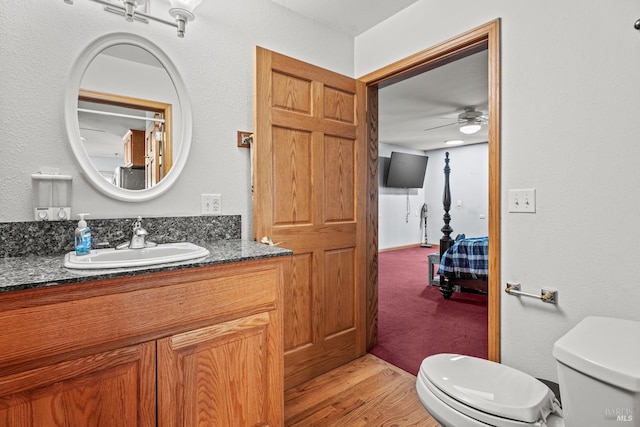 bathroom featuring hardwood / wood-style flooring, toilet, vanity, and ceiling fan