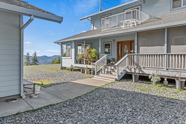 property entrance with a balcony, a mountain view, and covered porch