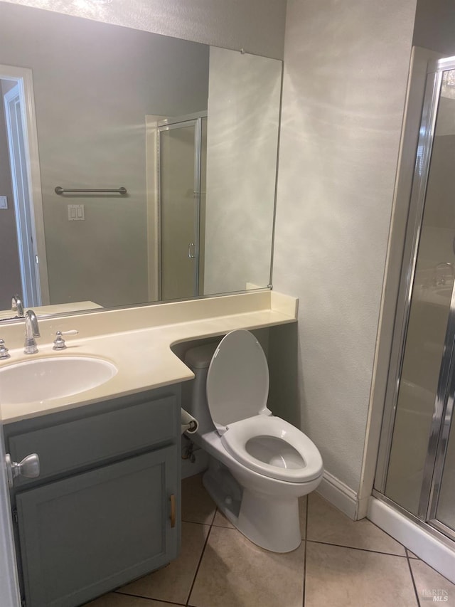 bathroom with toilet, vanity, tile patterned flooring, and a shower with door