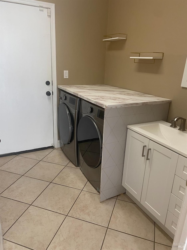 laundry room with light tile patterned floors, sink, separate washer and dryer, and cabinets