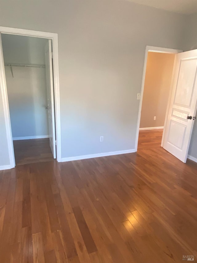 unfurnished bedroom with a closet and dark wood-type flooring