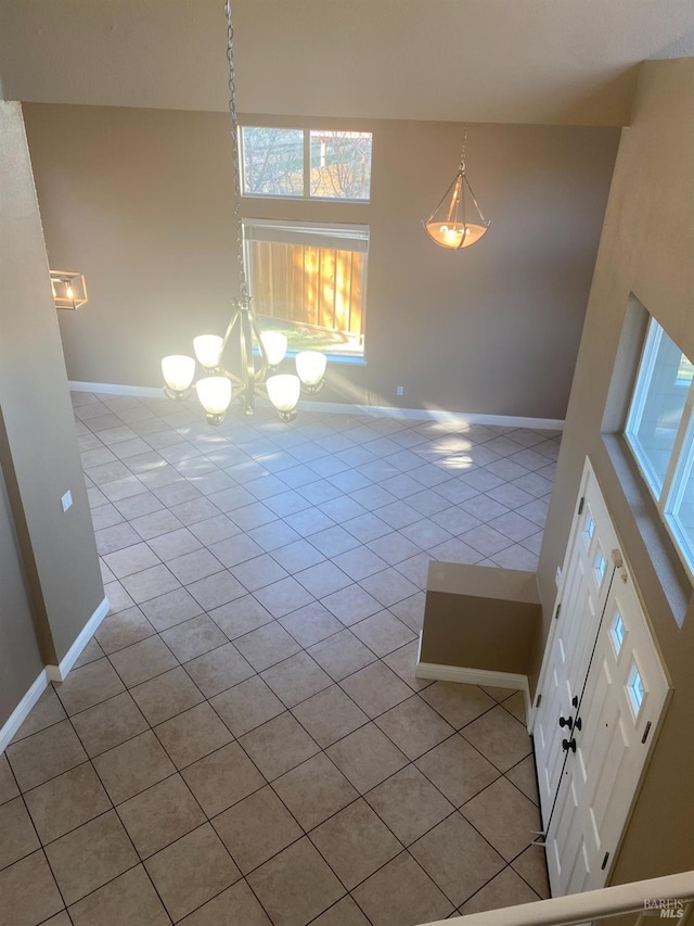 tiled empty room with a towering ceiling and an inviting chandelier