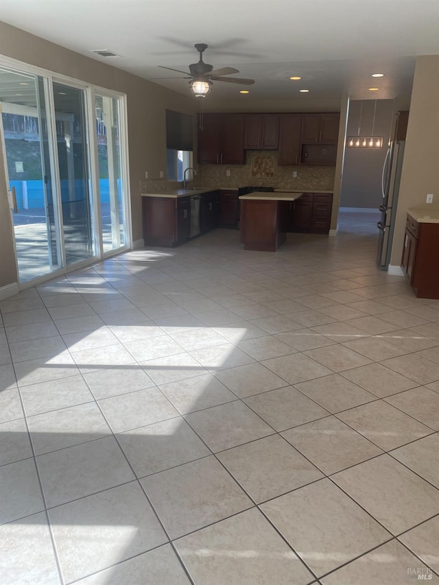 kitchen with ceiling fan, backsplash, sink, light tile patterned flooring, and stainless steel fridge