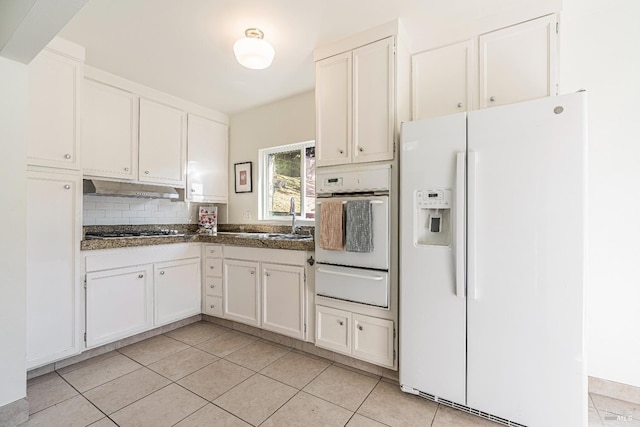 kitchen with backsplash, sink, light tile patterned floors, white appliances, and white cabinets