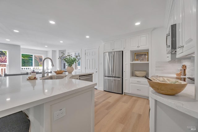 kitchen with light stone counters, white cabinetry, and stainless steel appliances