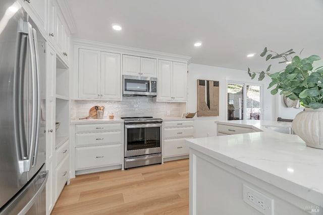 kitchen featuring light stone countertops, white cabinets, stainless steel appliances, backsplash, and light hardwood / wood-style flooring