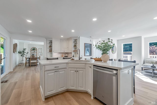 kitchen featuring sink, white cabinetry, stainless steel dishwasher, and a center island with sink