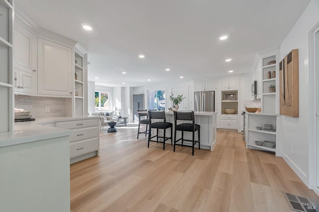 kitchen with backsplash, white cabinetry, a breakfast bar area, and stainless steel fridge