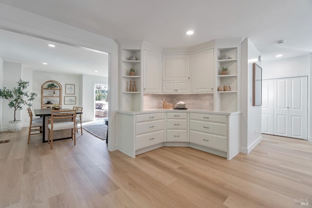 kitchen with white cabinets, light hardwood / wood-style floors, and tasteful backsplash