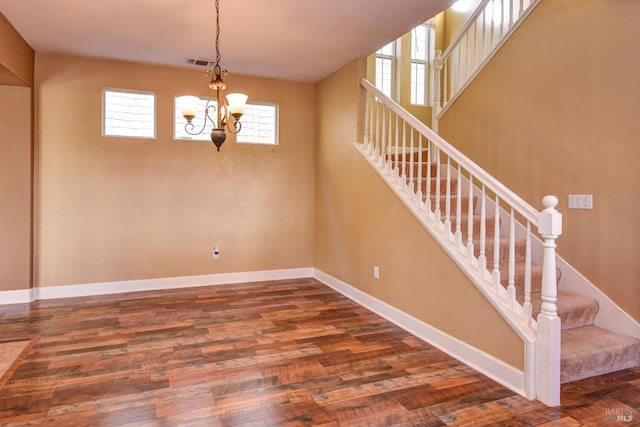 staircase featuring hardwood / wood-style flooring and a notable chandelier