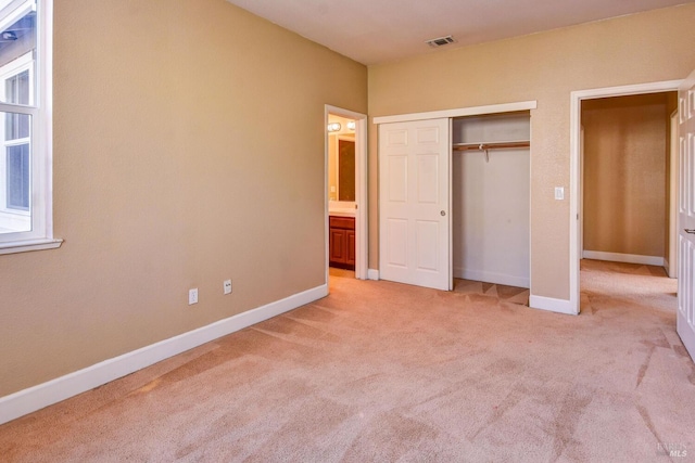 unfurnished bedroom with a closet and light colored carpet