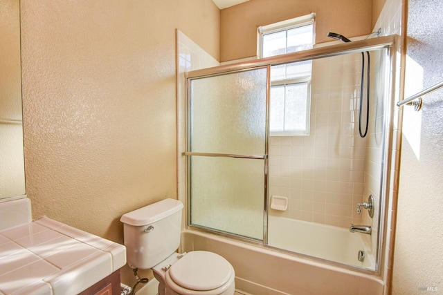 bathroom with toilet and combined bath / shower with glass door