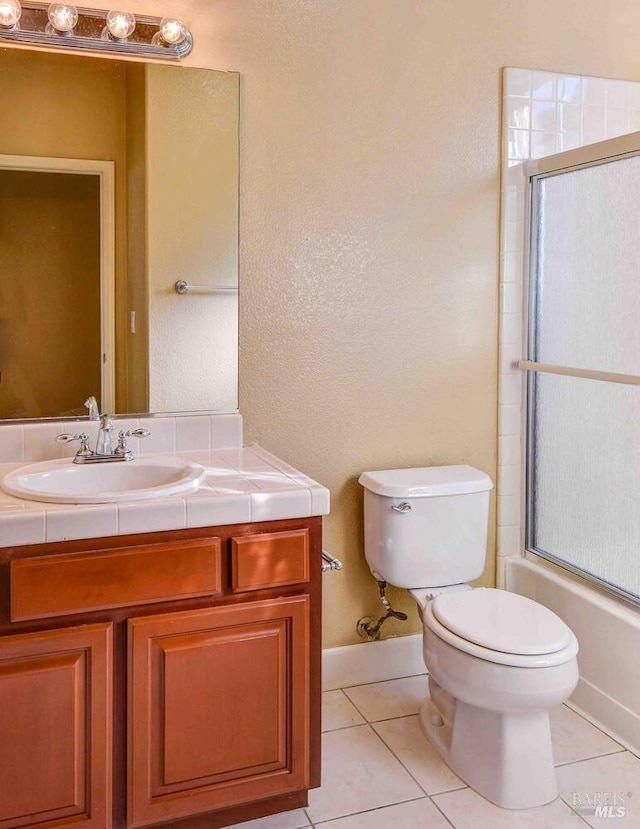 full bathroom featuring toilet, vanity, tile patterned flooring, and bath / shower combo with glass door