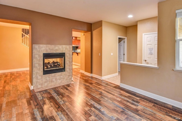 unfurnished living room featuring hardwood / wood-style flooring and a tile fireplace