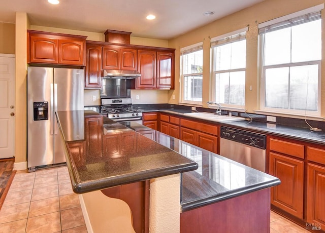 kitchen with dark stone countertops, a center island, sink, stainless steel appliances, and light tile patterned floors