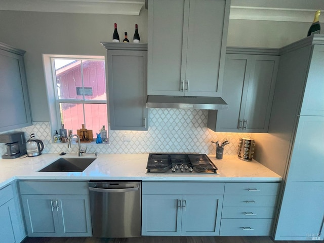 kitchen with appliances with stainless steel finishes, light stone counters, tasteful backsplash, and sink