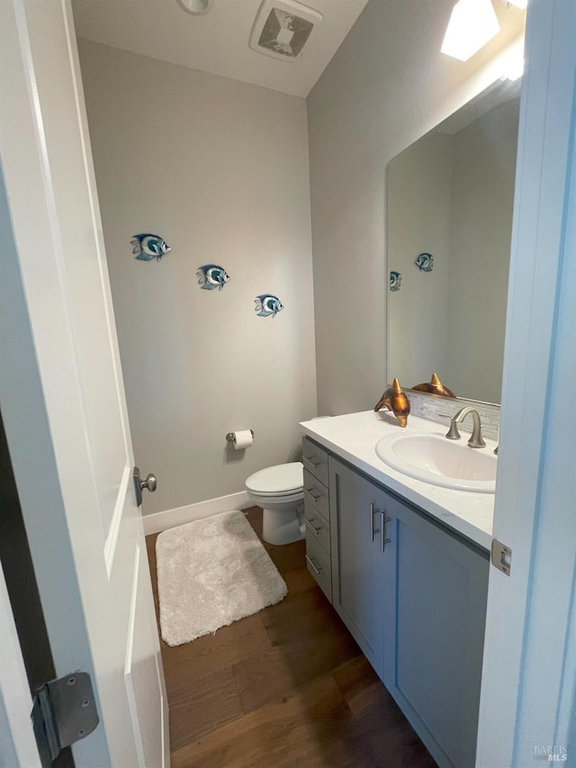 bathroom featuring toilet, hardwood / wood-style flooring, and vanity