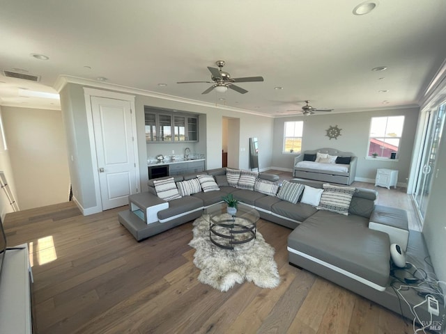 living room with indoor wet bar, crown molding, and wood-type flooring