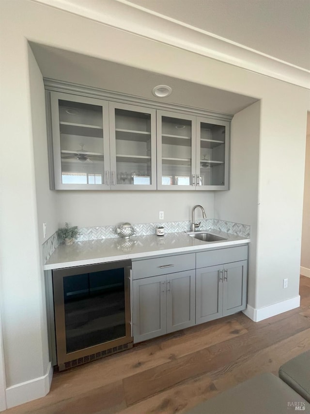 bar featuring sink, dark hardwood / wood-style floors, gray cabinetry, and wine cooler