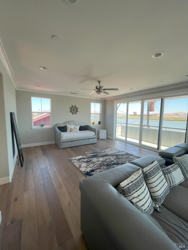 living room featuring a wealth of natural light, ornamental molding, a water view, and light hardwood / wood-style flooring