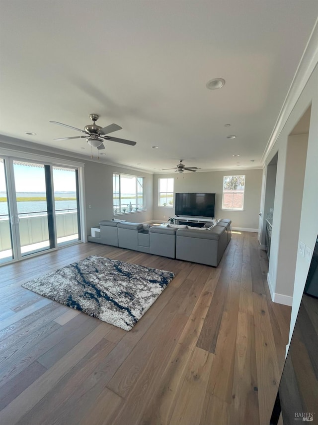 unfurnished living room featuring ceiling fan, ornamental molding, a water view, and hardwood / wood-style floors
